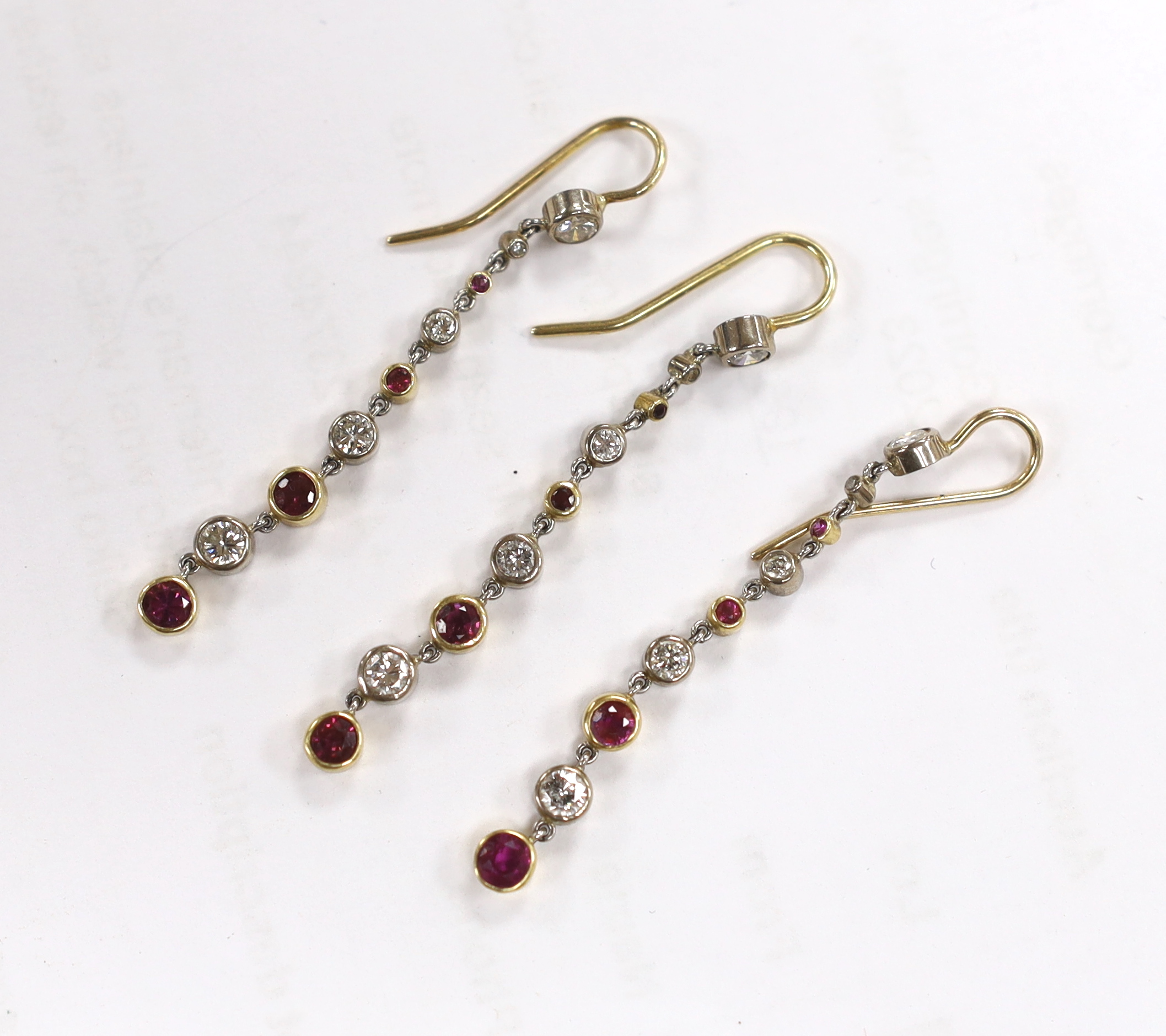 Three yellow metal and graduated ruby and diamond cluster set line drop earrings, overall 50mm, gross weight 5.7 grams.